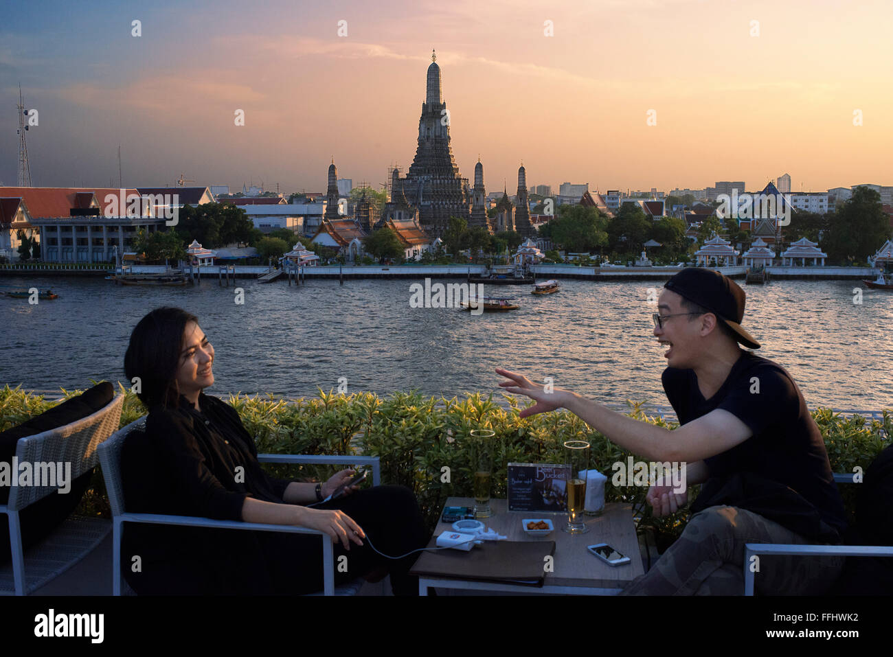 Couple of lovers. Landscape in sunset of Wat Arun Temple from Chao Praya River from the roof of Sala Rattanakosin Hotel. Bangkok Stock Photo