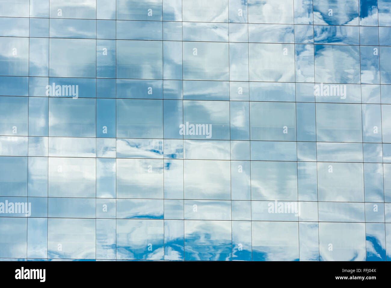 blue sky and clouds reflected in windows of modern office building ...