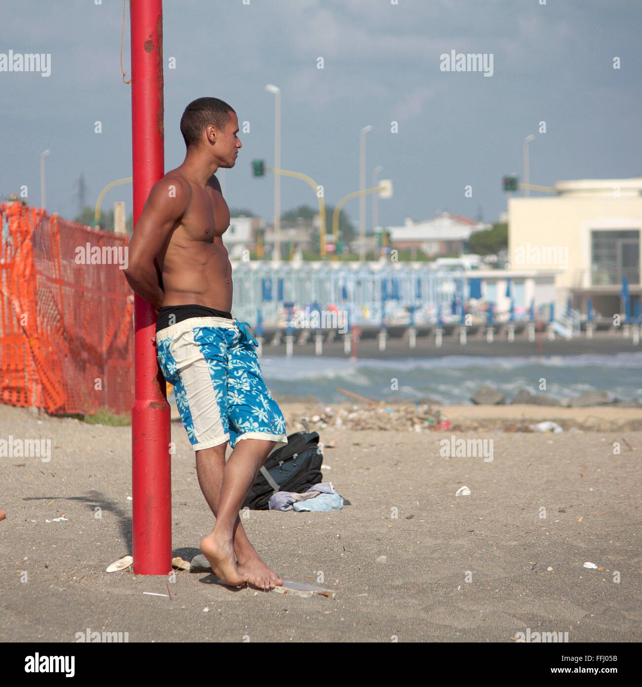 OSTIA, ITALY - JUNE 19, 2010: unidentified young man stands next to a pole in the beach of Ostia. Stock Photo