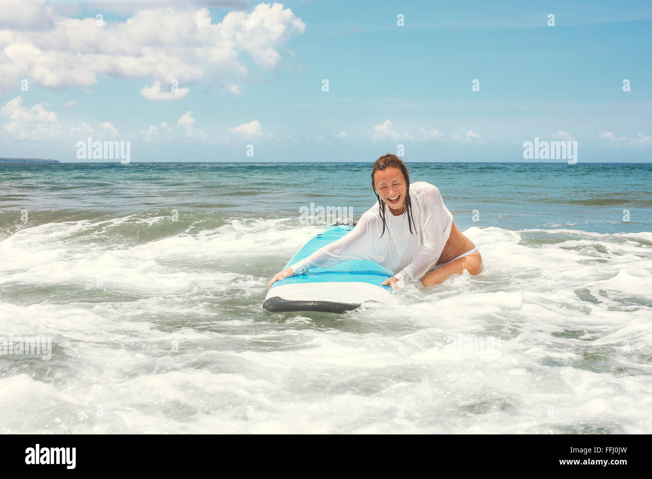 Girl on the waves in the ocean with her Surfboard. Stock image Stock Photo