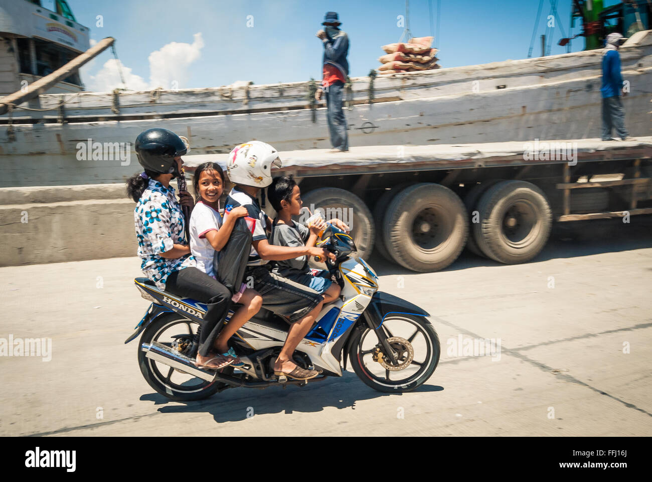 Two adults and two children riding the same motorcycle through the