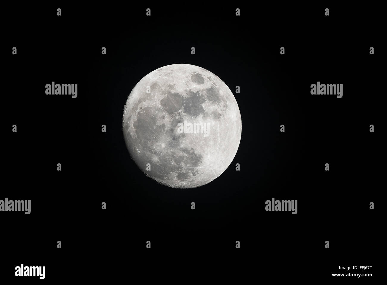 Image of a full moon shot during the evening shows the moonlight highlighting features of the planet. Stock Photo