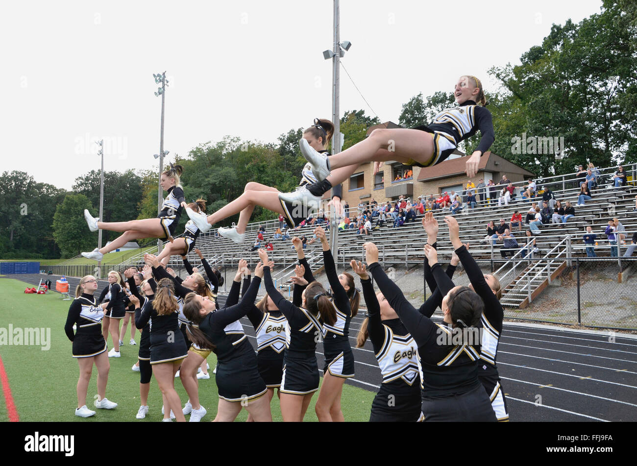 high school cheerleaders perform at a football game Stock Photo
