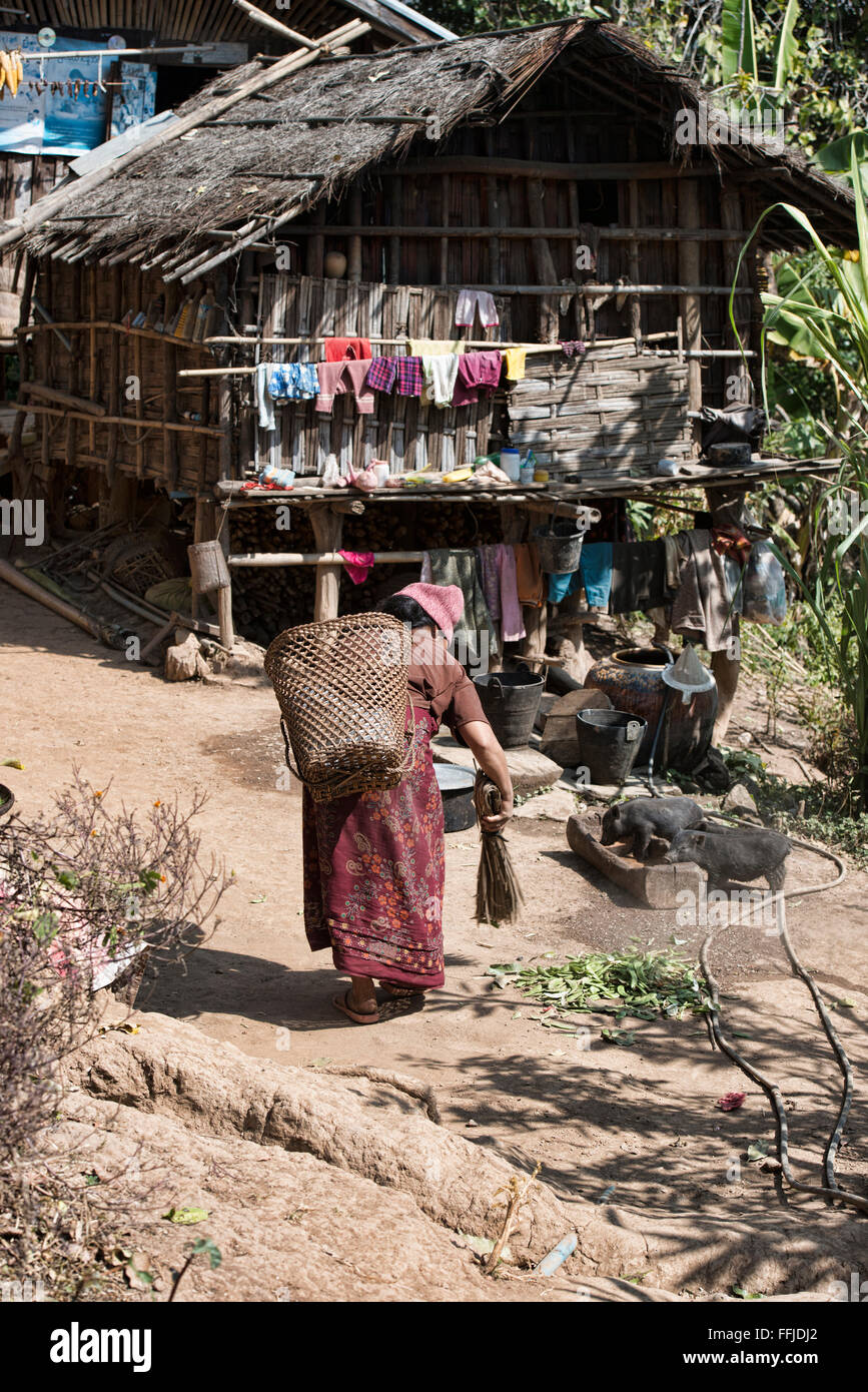 Muun tribal woman sweeping her homefront in rural Chin State, Myanmar Stock Photo
