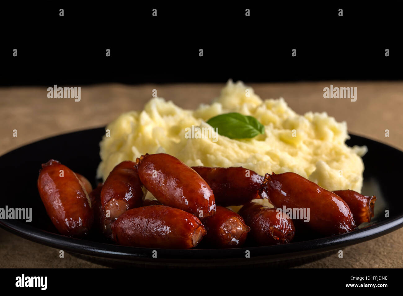 Sausage with mashed potatoes on dark plate Stock Photo