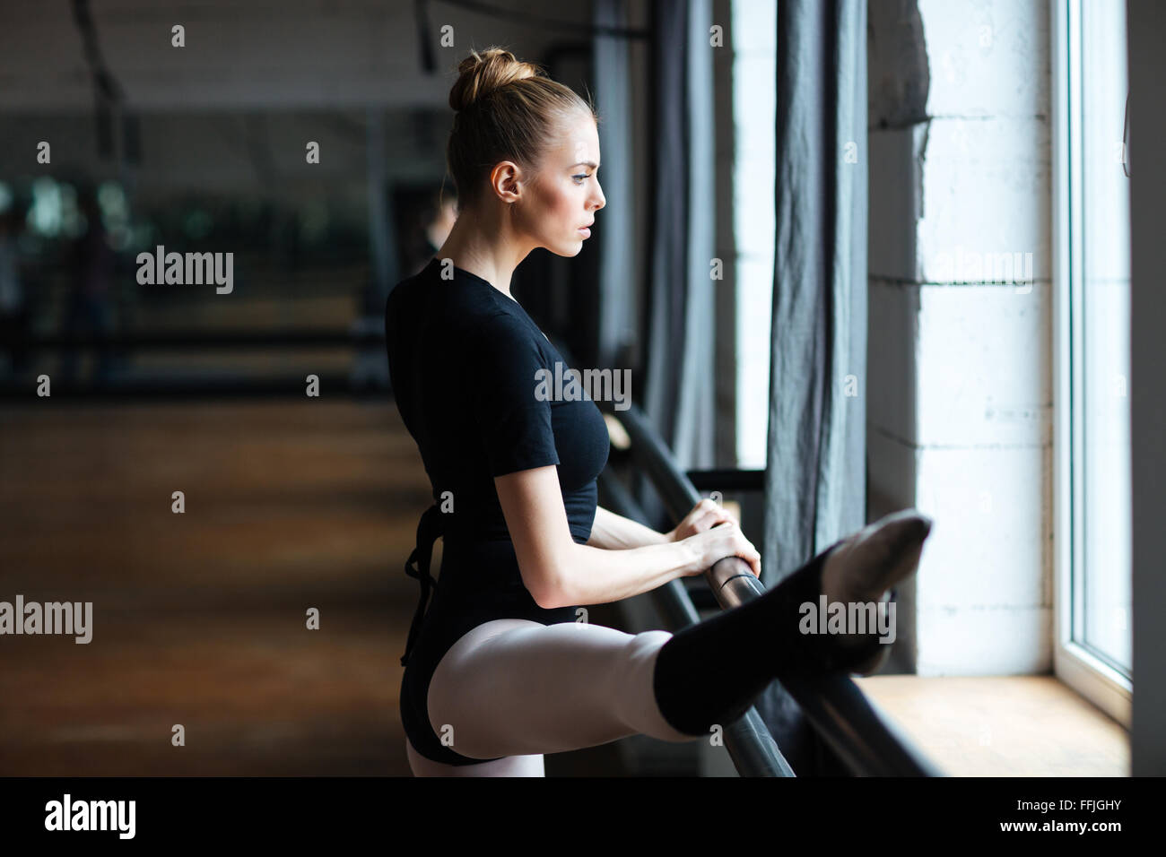 Attractive ballerina stretching leg in ballet class Stock Photo