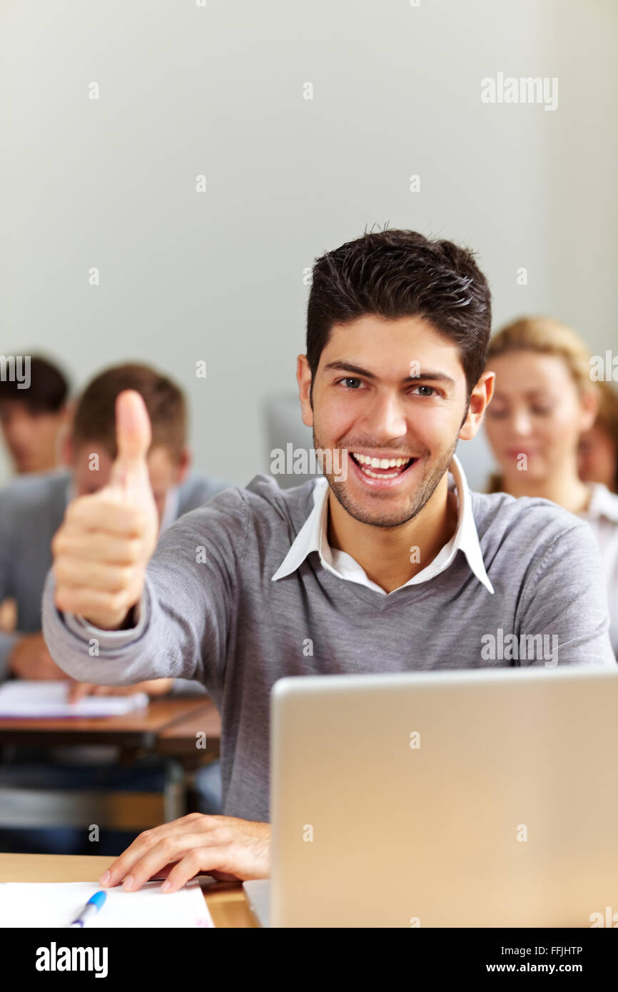 Successful student at laptop holding his thumbs up Stock Photo - Alamy