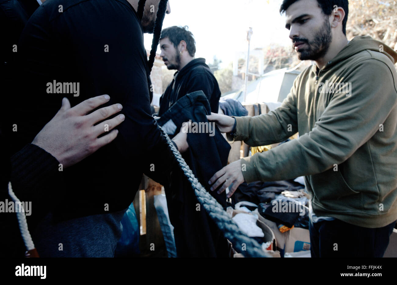 Aris and Nikos from Platanos give male warm refugees clothes to change their wet ones in Platanos camp. Stock Photo