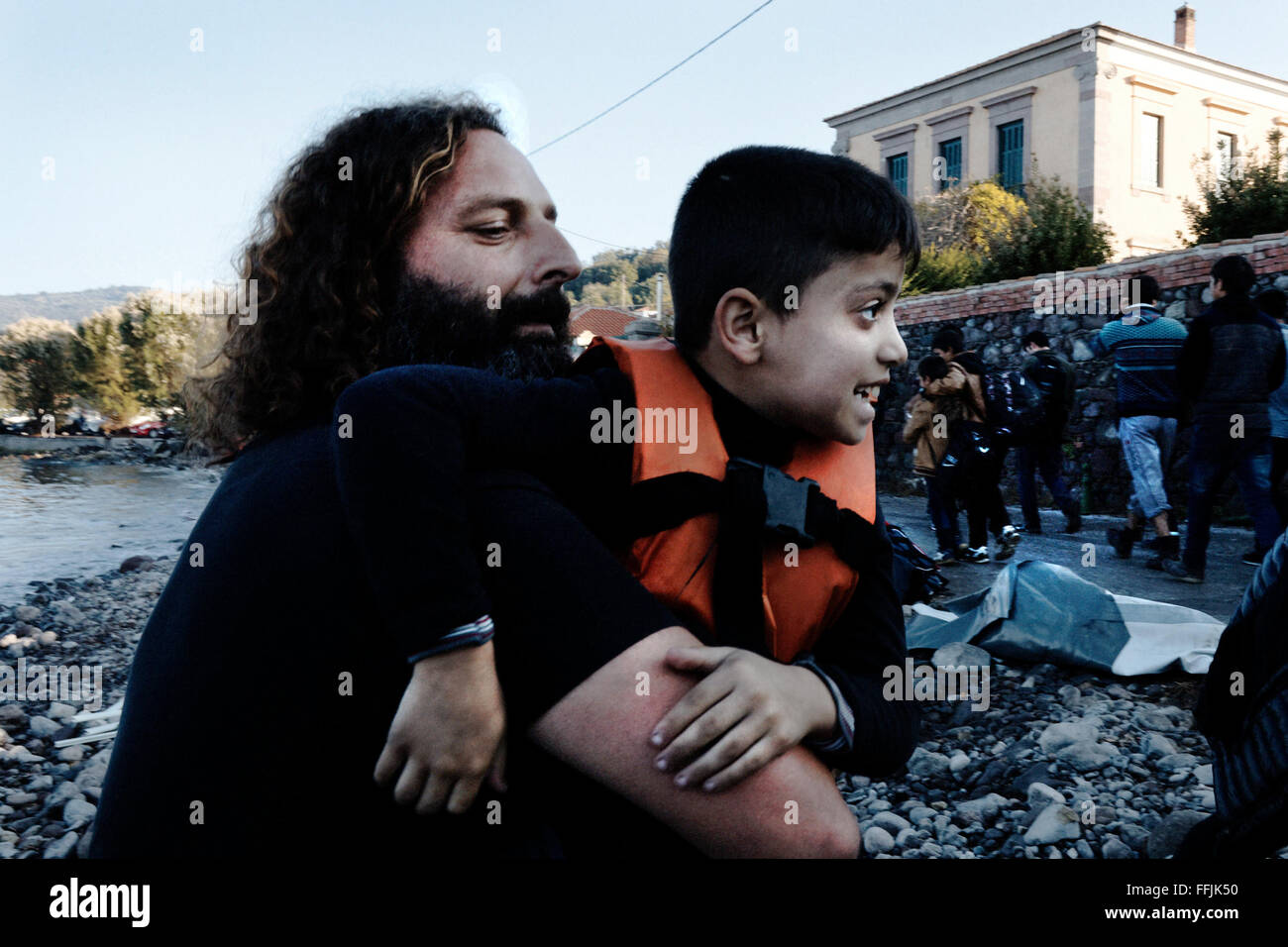 Vasilis, 42 takes a young Syrian out of the boat, after having crossed the 7,5 miles of sea between the Turkish coast and lesvos Stock Photo