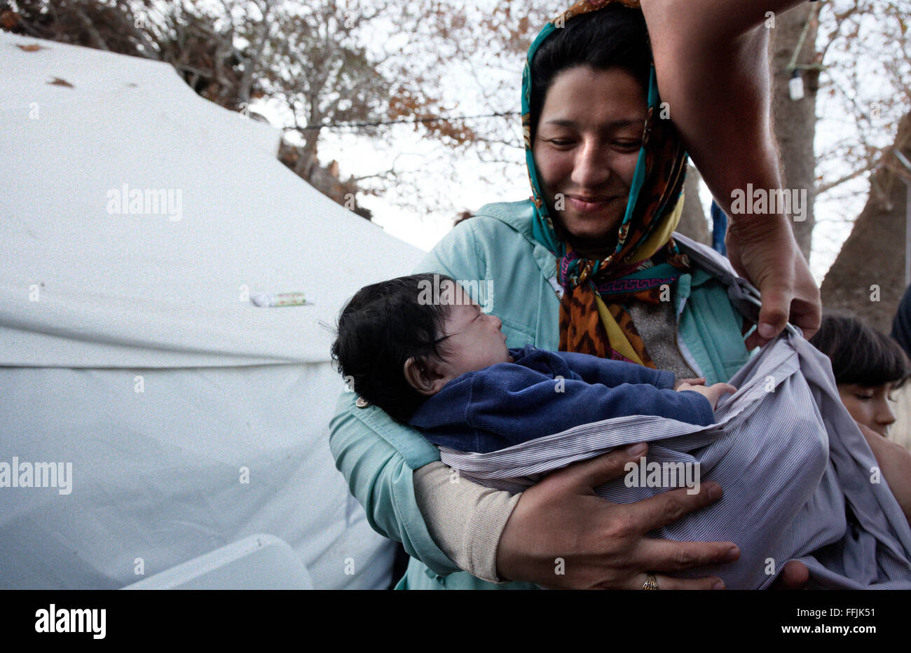 young Afgan mother is been shown how to wear a carrier for her baby in Platanos camp. Stock Photo
