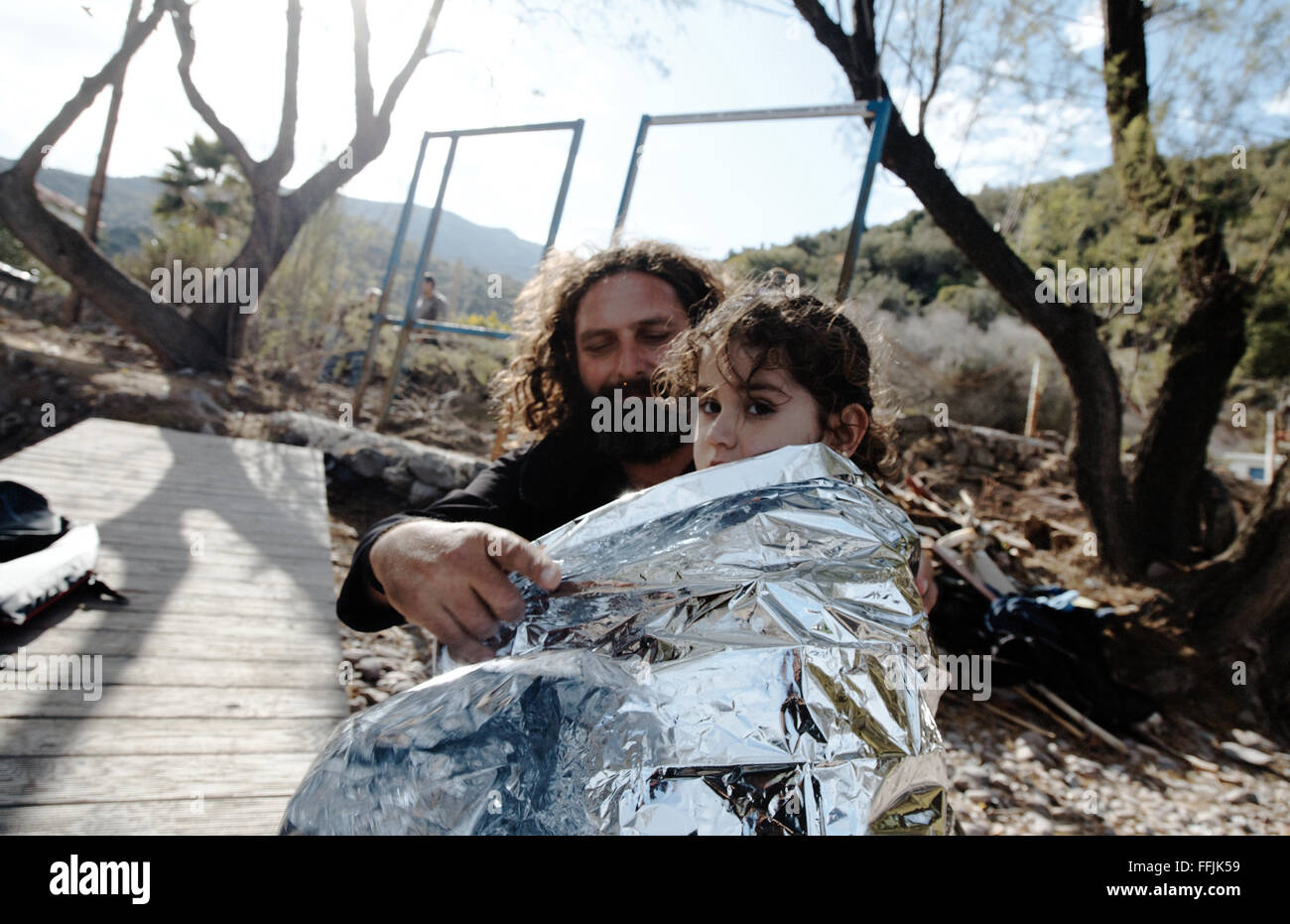 Vasilis, 42 covers a young Syrian girl in an isothermic blanket, after having crossed the 7,5 miles of sea between the Turkish Stock Photo