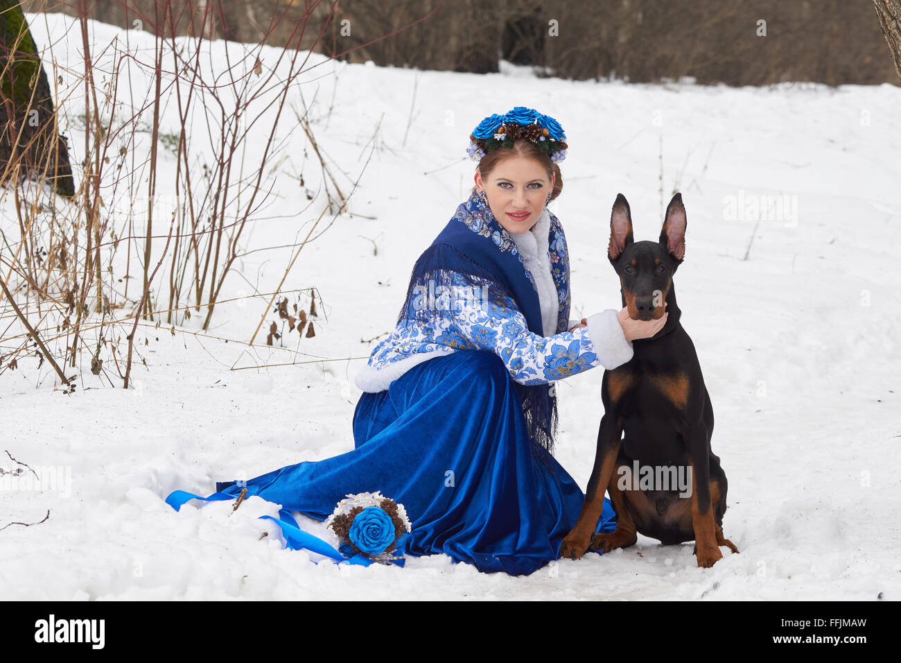 Young russian woman in traditional winter clothing with Doberman Pinscher Stock Photo