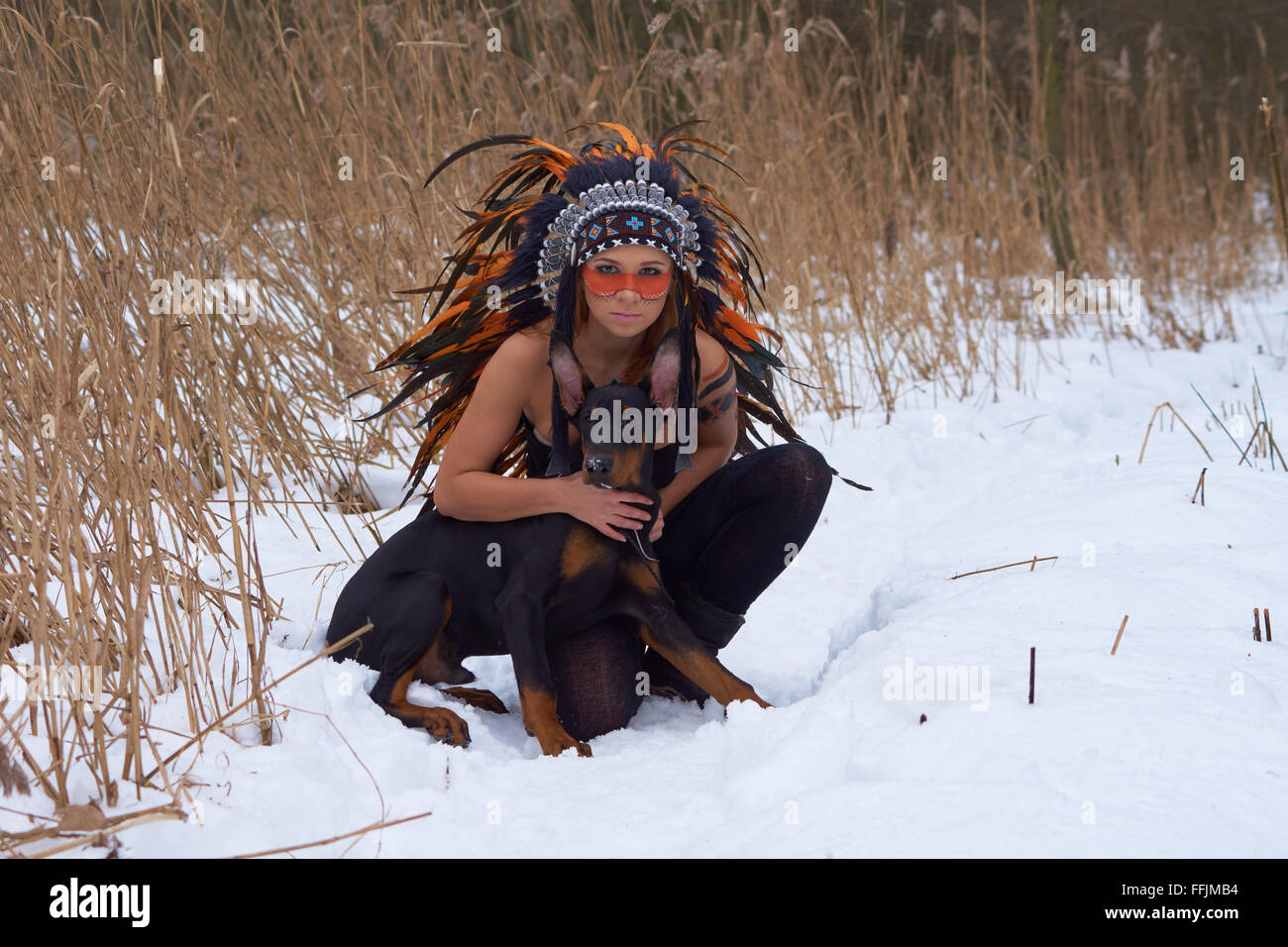 Girl in native american headdress with Doderman Pinscher Stock Photo