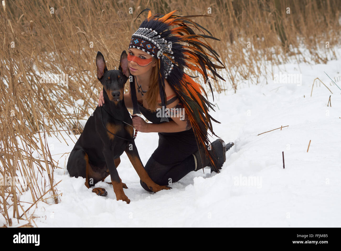 Girl in native american headdress with Doderman Pinscher Stock Photo