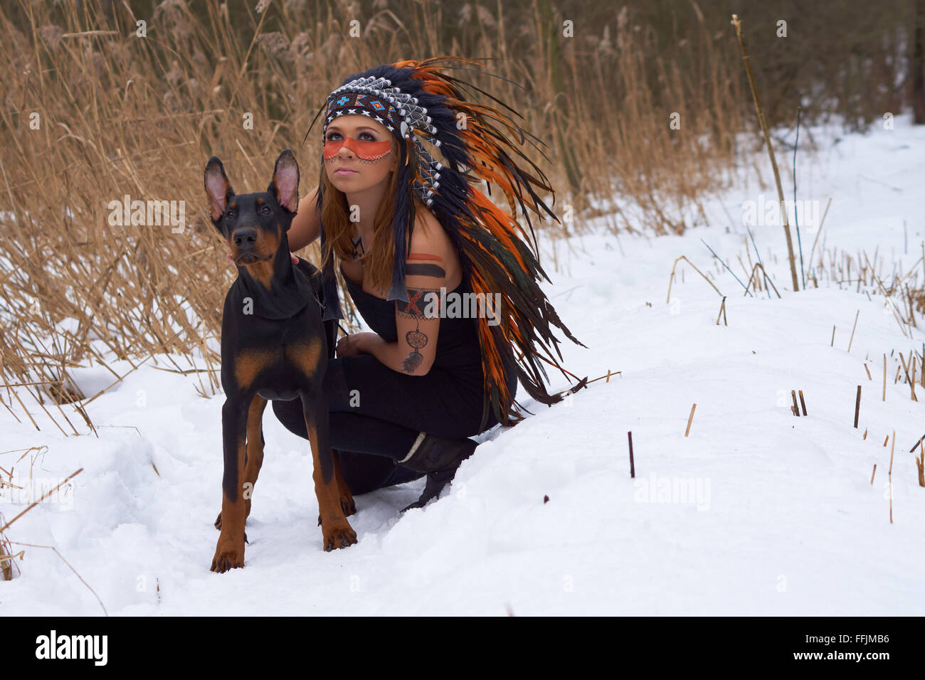 Girl in native american headdress with Doderman Pinscher Stock Photo