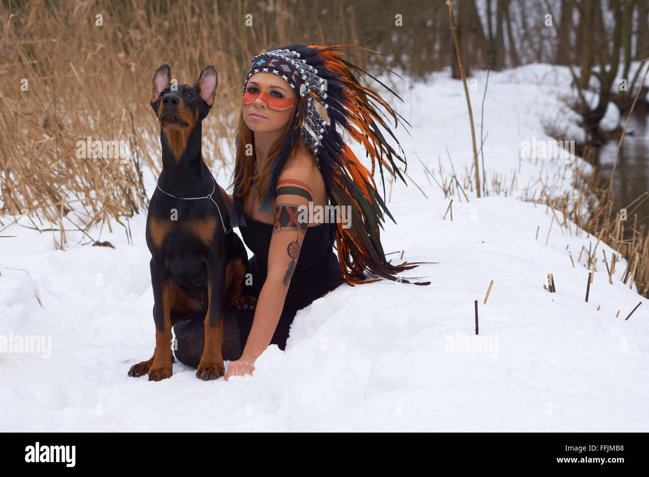 Girl in native american headdress with Doberman Pinscher Stock Photo