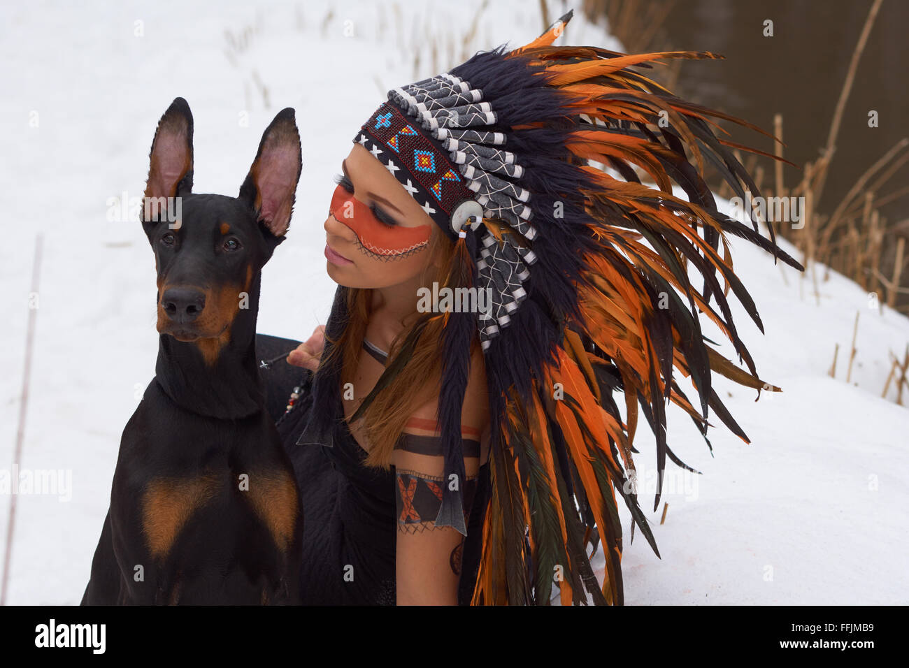 Girl in native american headdress with Doberman Pinscher Stock Photo