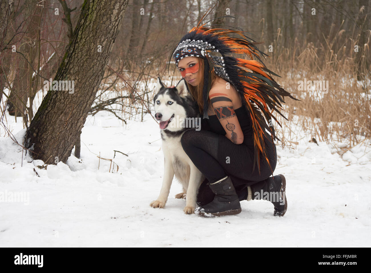 Girl in native american headdress with Siberian Husky Stock Photo