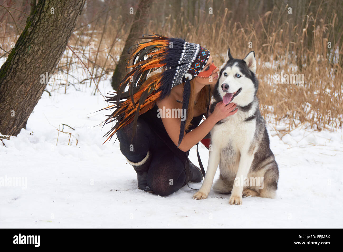 Girl in native american headdress likes her Siberian Husky Stock Photo