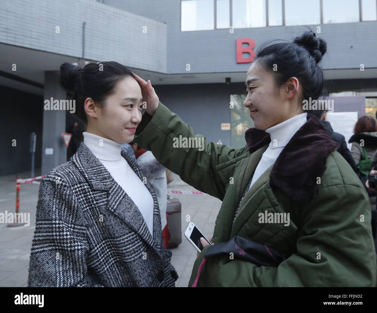 (160215) -- BEIJING, Feb. 15, 2016 (Xinhua) -- Candidate Li Lujia (R) combs her twin sister Li Luxi's hair outside the examination hall at Beijing Film Academy (BFA) in Beijing, capital of China, Feb. 15, 2016. The annual entrance exam of China's art colleges including BFA, the Central Academy of Drama and the Communication University of China started simultaneously on Monday. Over 7,600 applicants for BFA's performance institute will take part in the exam to vie for 45 vacancies in the institute. Some Chinese young people regarded studying in an art college as a shortcut to become famous in r Stock Photo