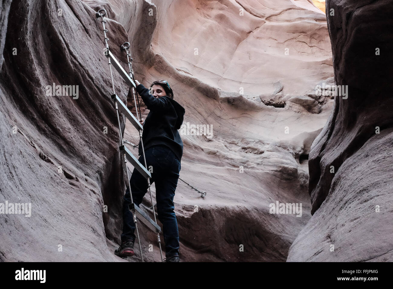 A hiker carefully descends the cliffs in the Red Canyon in the mountains engulfing Eilat, at the southern most tip of Israel on Stock Photo