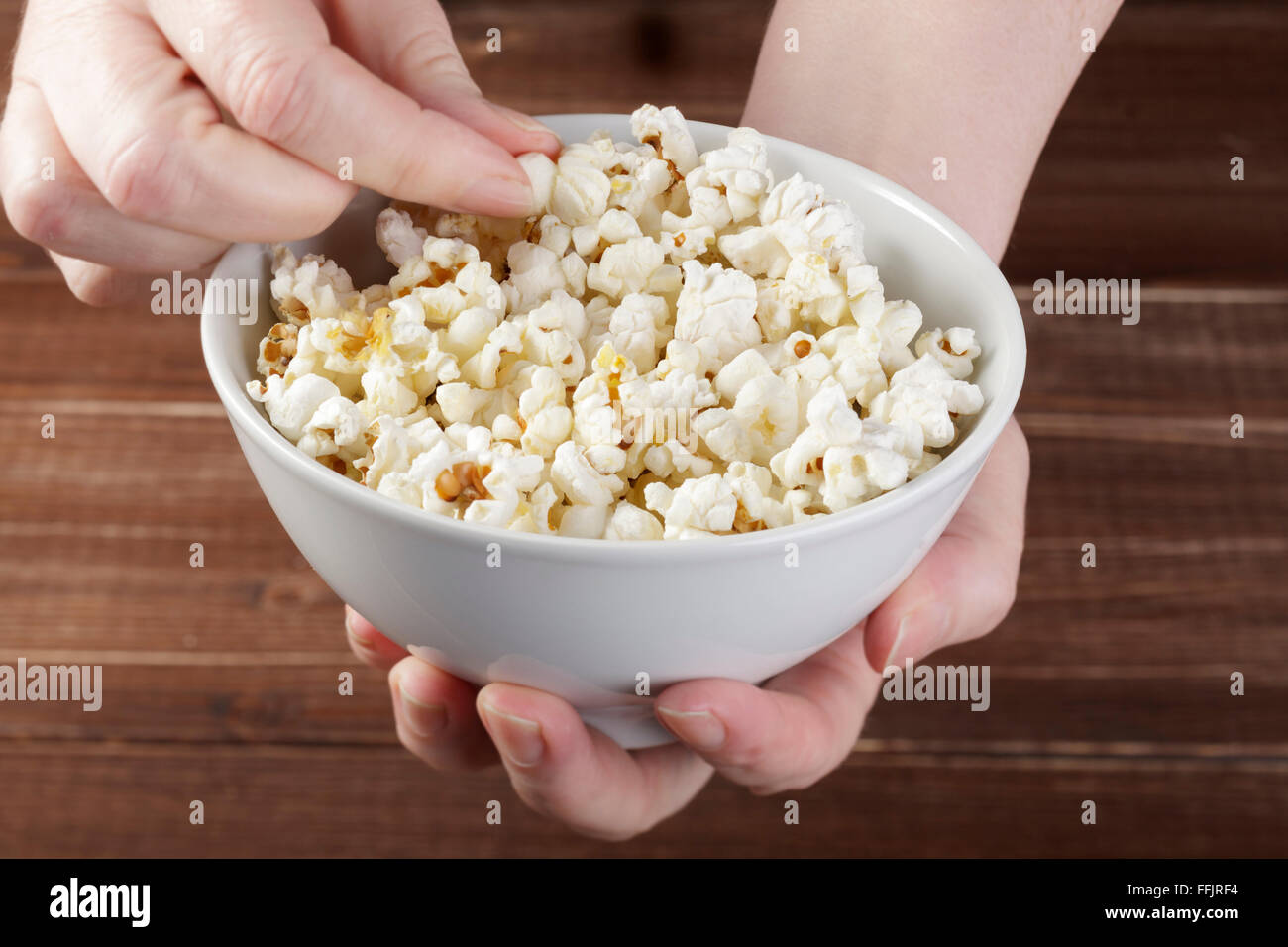 Hands holding bowl of popcorn Stock Photo