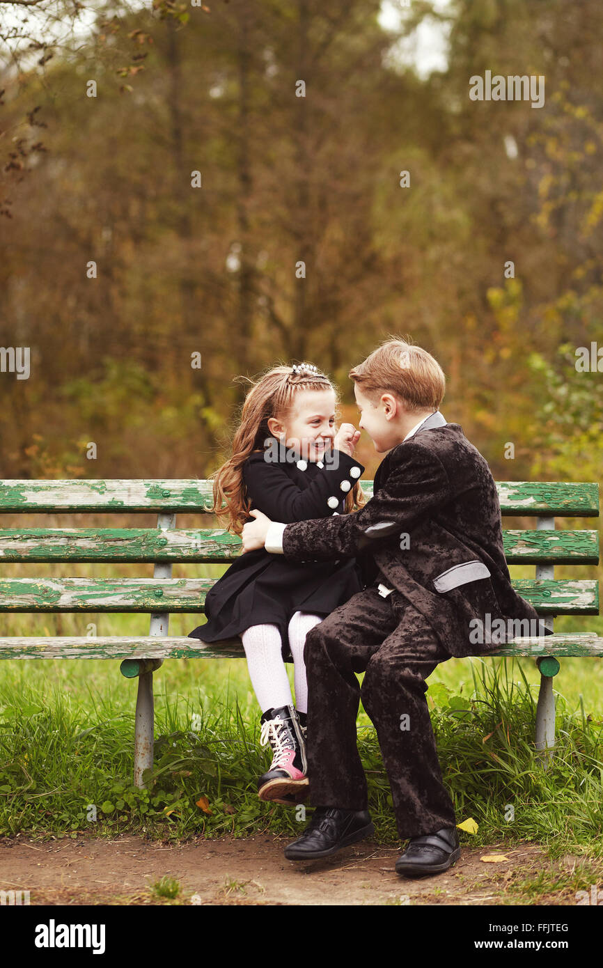 Brother and sister kids hugging on a bench Stock Photo
