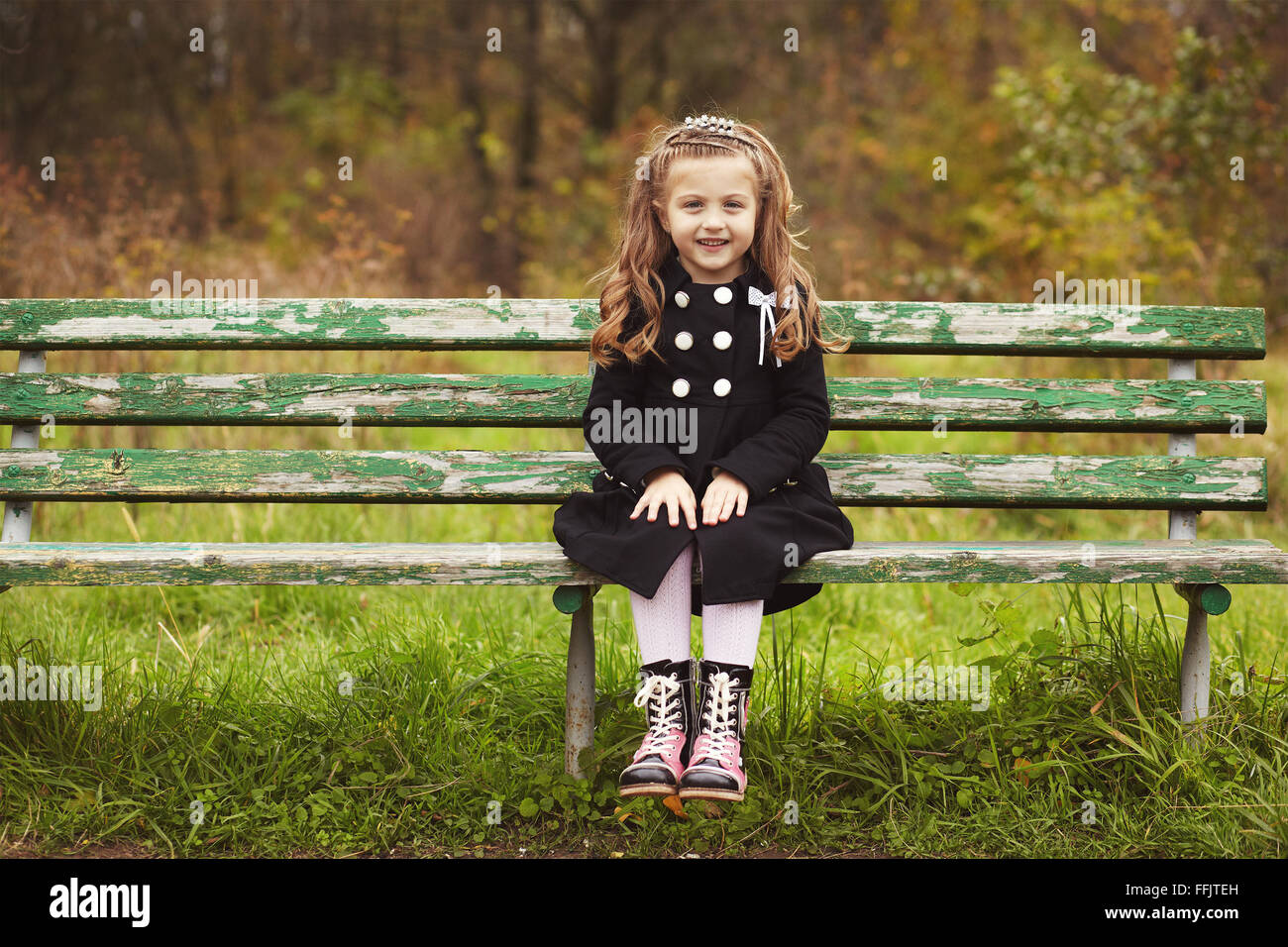 Cute little girl sitting on a bench Stock Photo