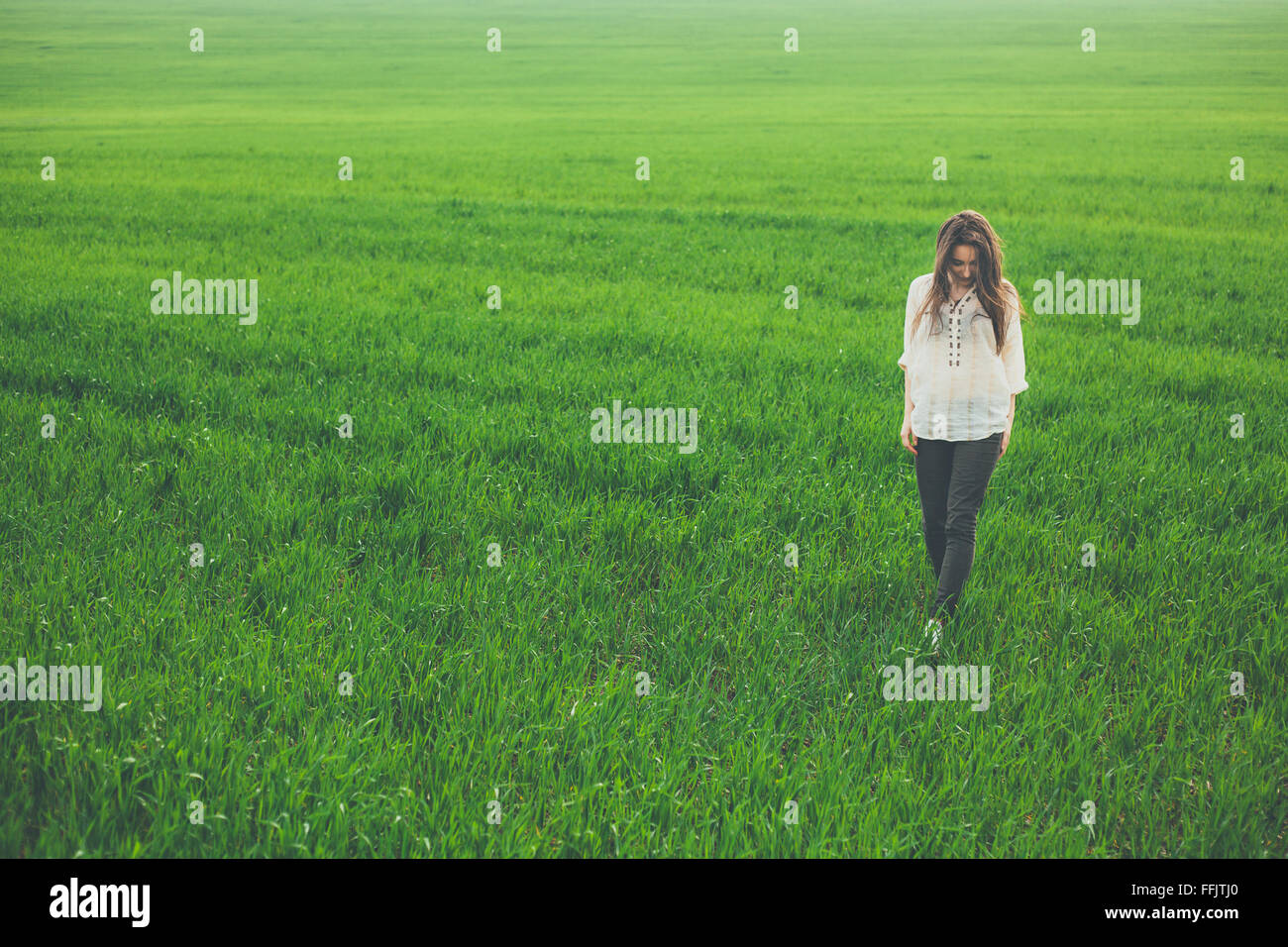 Sad lonely girl in green field Stock Photo
