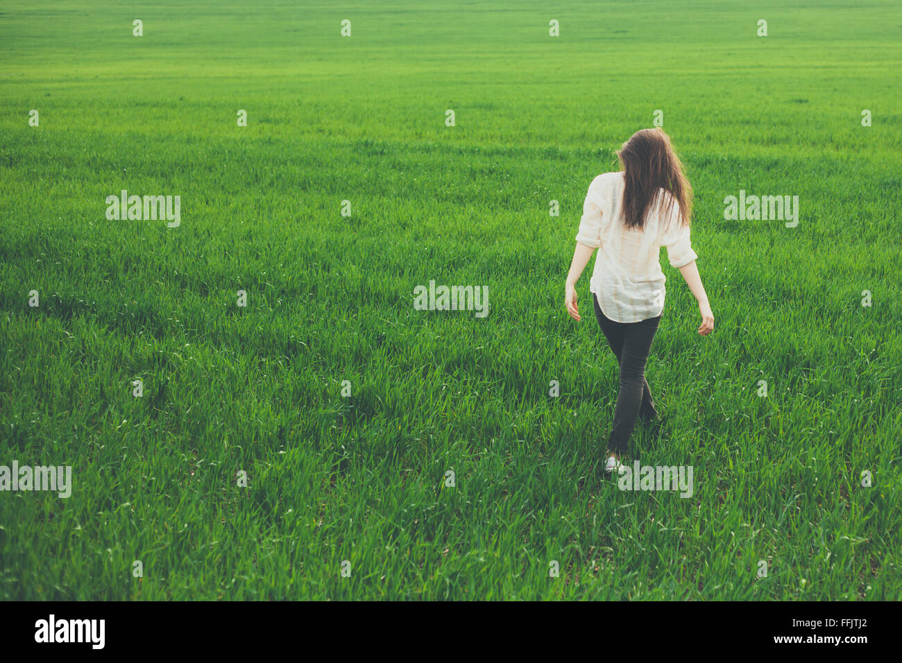 Back view of lonely girl in meadow Stock Photo