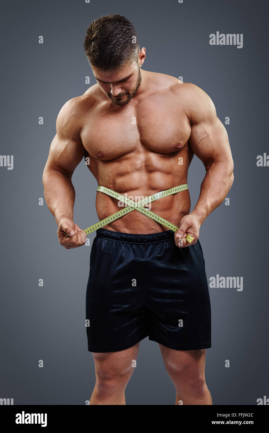 Bodybuilder measuring waist with tape measure Stock Photo