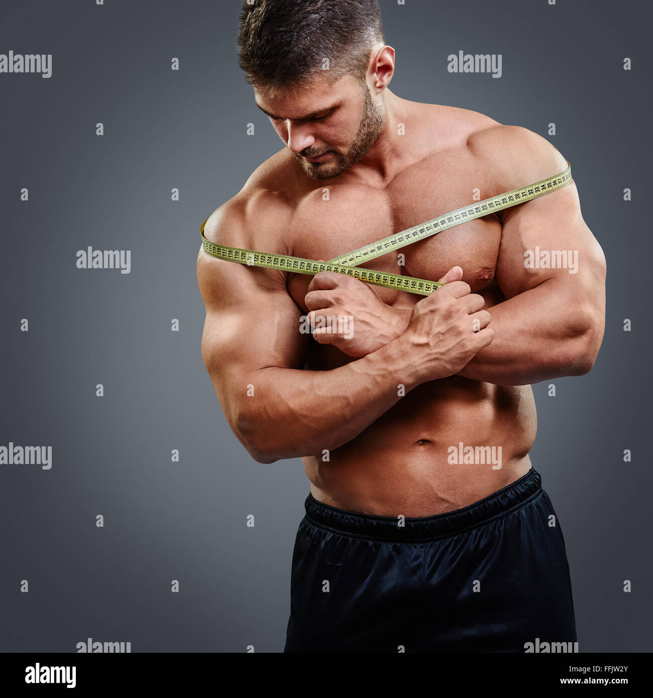 Bodybuilder measuring shoulders with tape measure Stock Photo