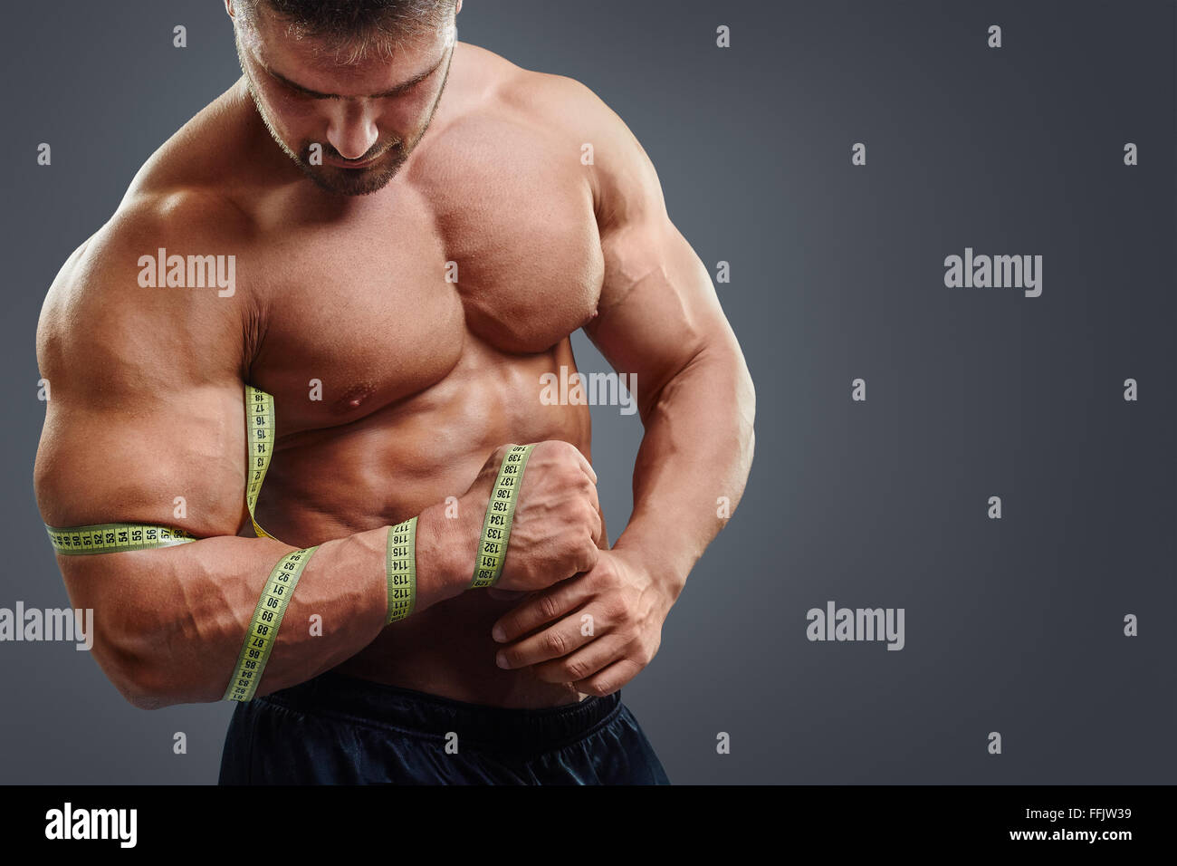 Bodybuilder measuring biceps with tape measure Stock Photo