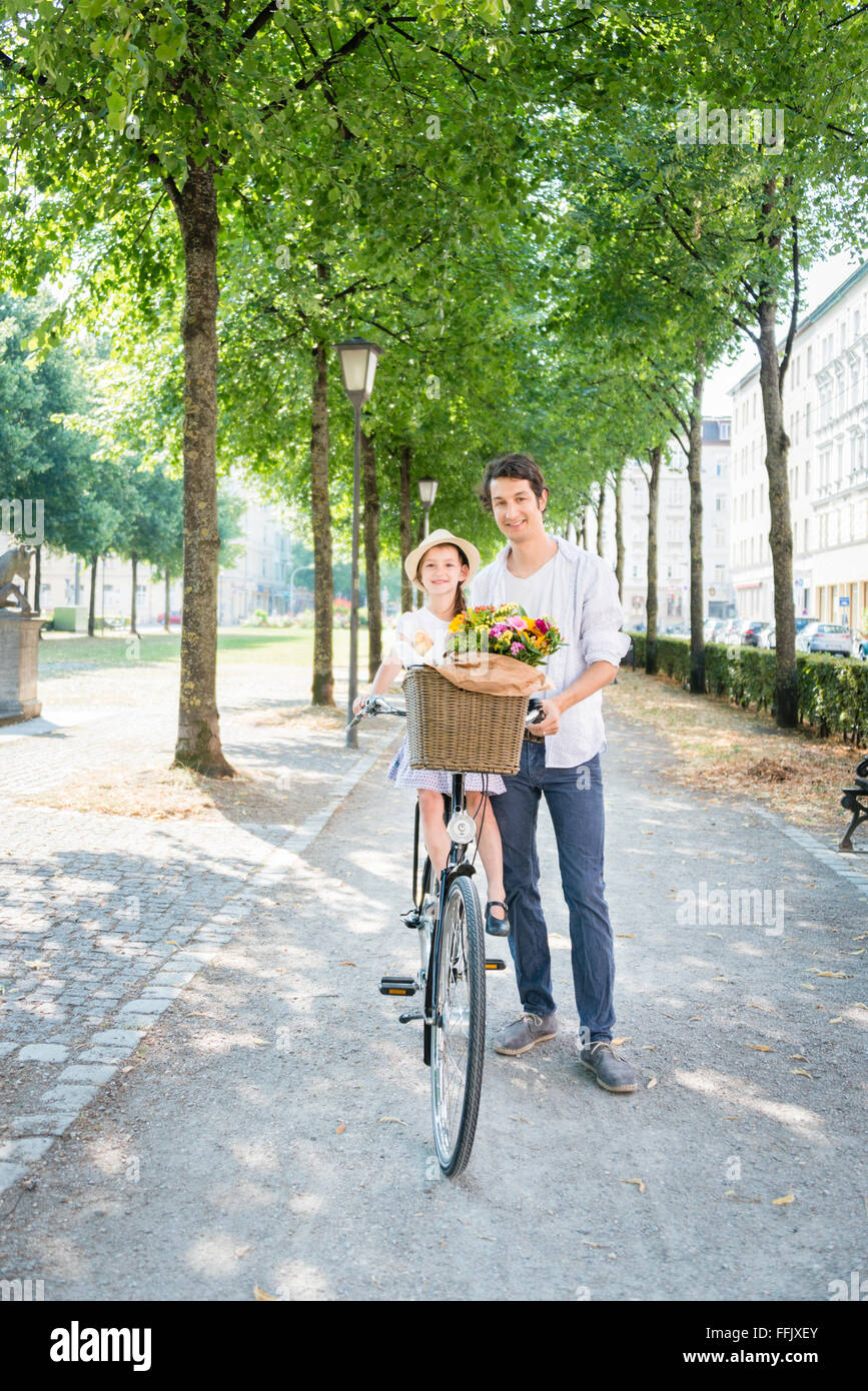 Father and daughter with bicycle and flowers Stock Photo