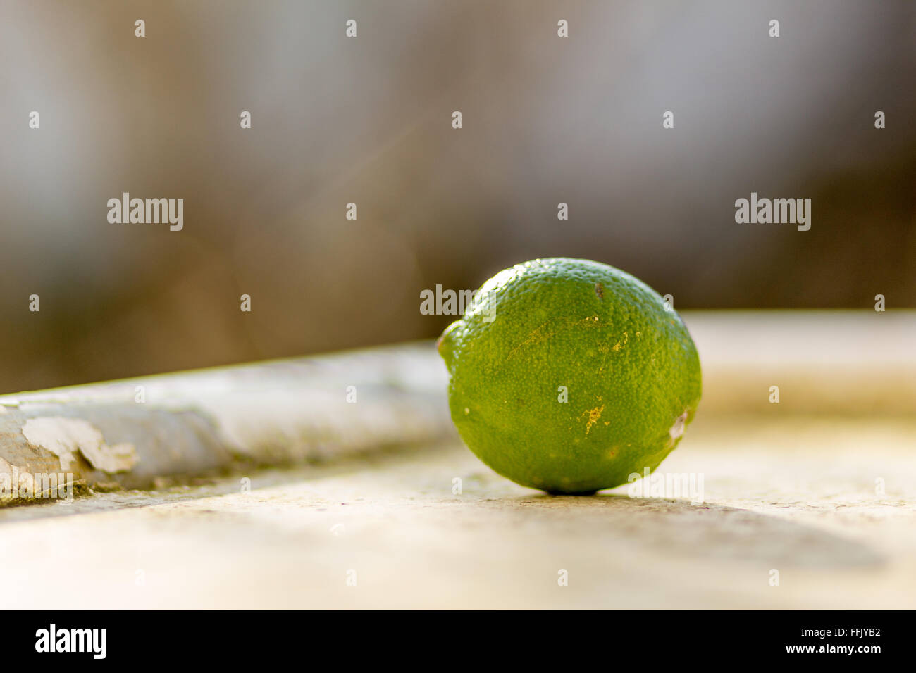 green lime outside on a metal window sill balcony with peeling white paint Stock Photo