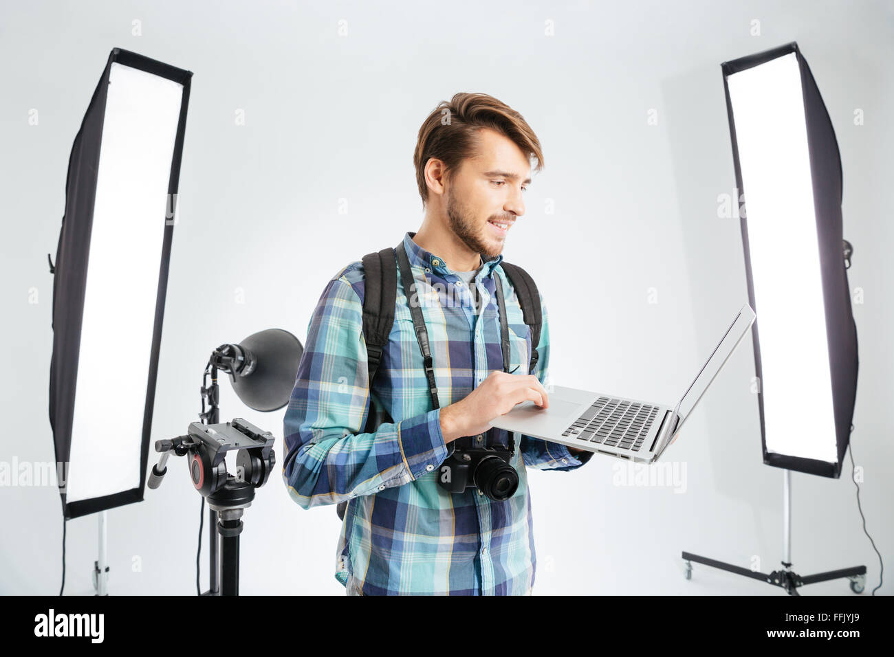 Happy male photographer using laptop computer in photo studio with ...