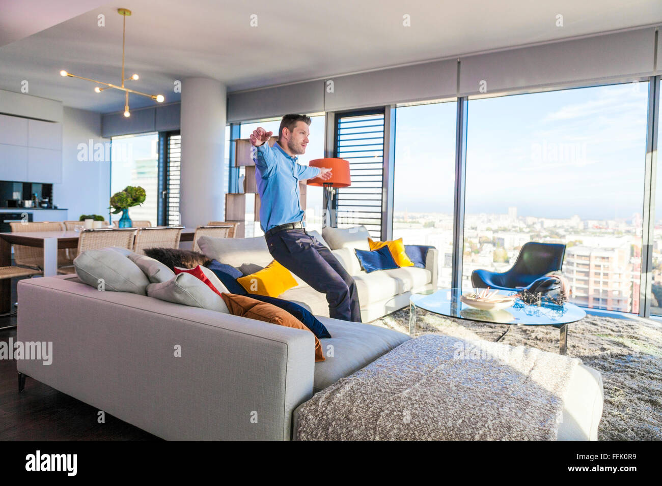 Man in apartment relaxing arms outstretched Stock Photo