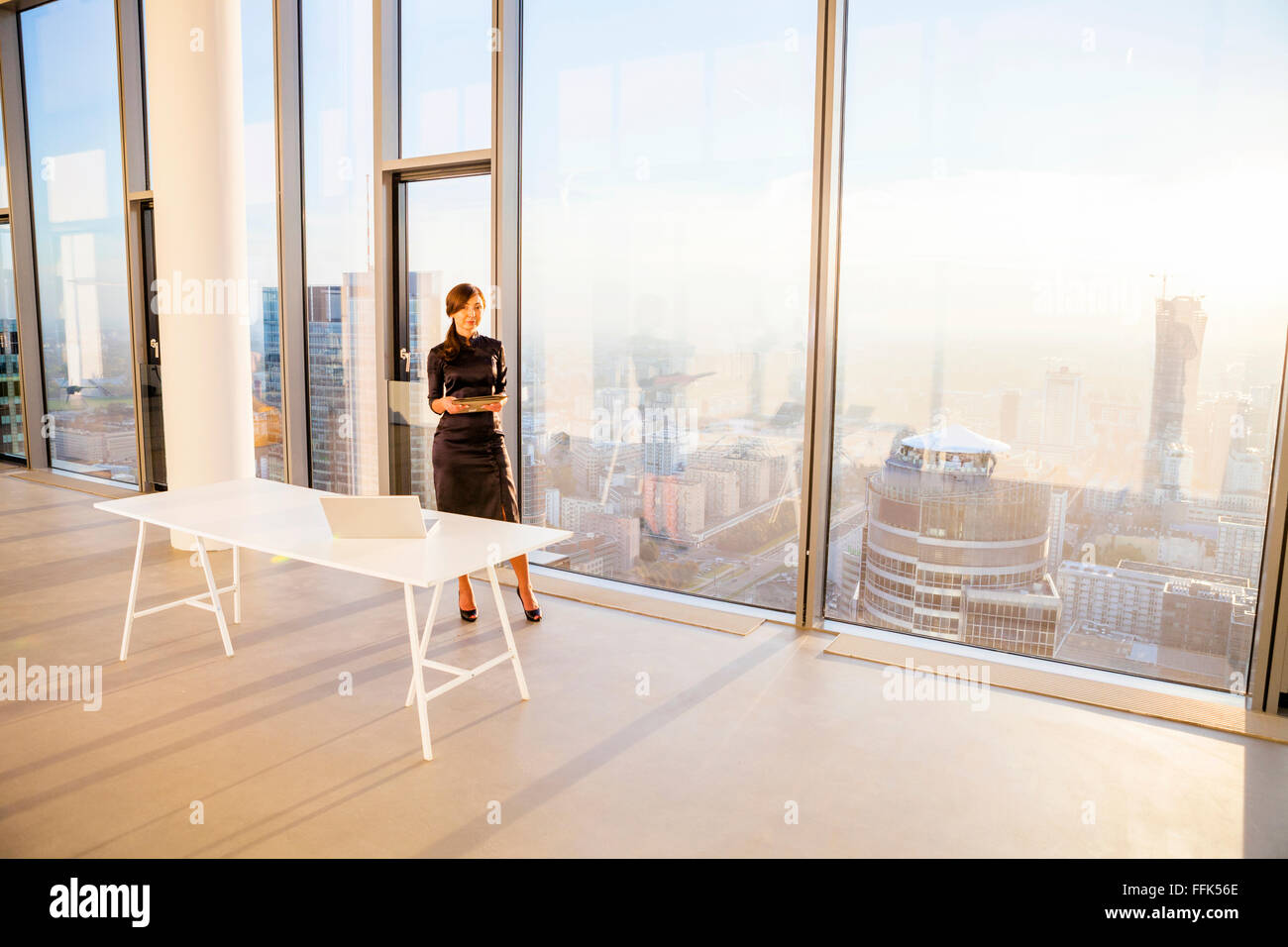 Female architect in office with urban skyline in background Stock Photo