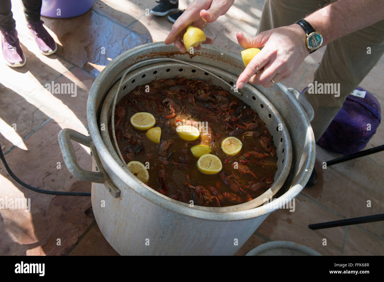 Squeezing lemon juice into the crawfish boil. Stock Photo