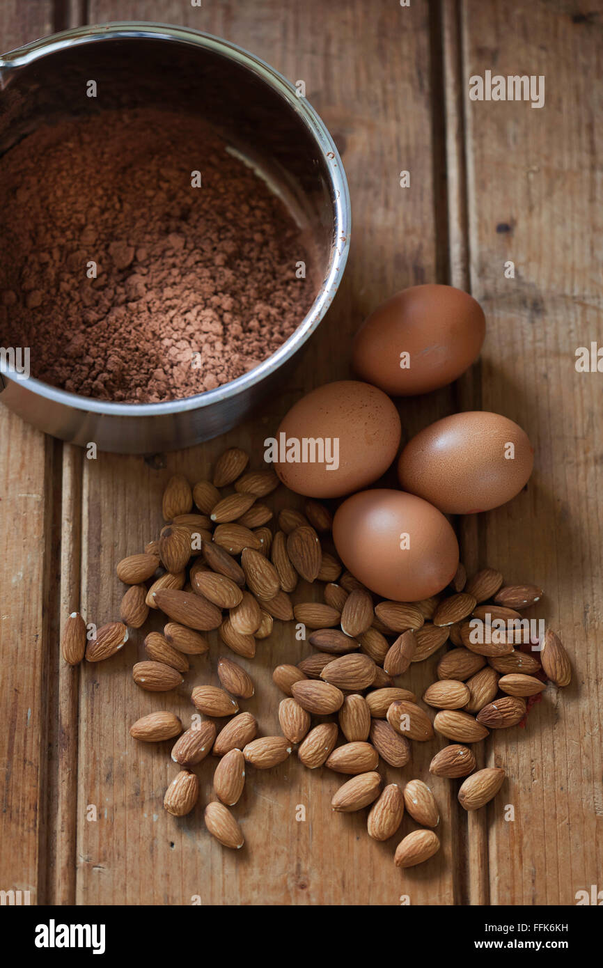 Almonds, cacao powder and eggs as baking ingredients on wooden background Stock Photo