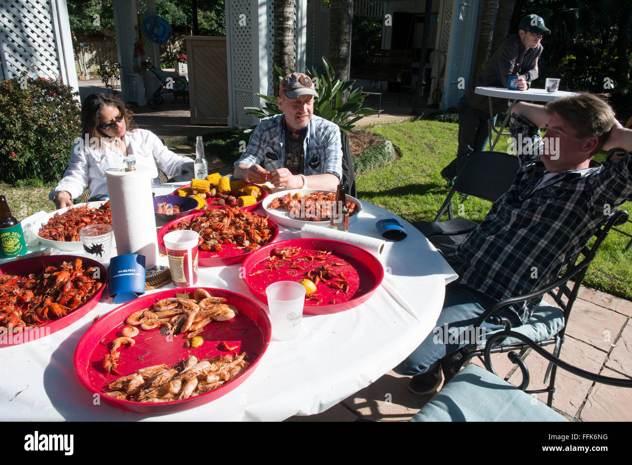 New Orleans family and friends sitting around the table at a traditional backyard crawfish boil, peeling crawfish. Stock Photo