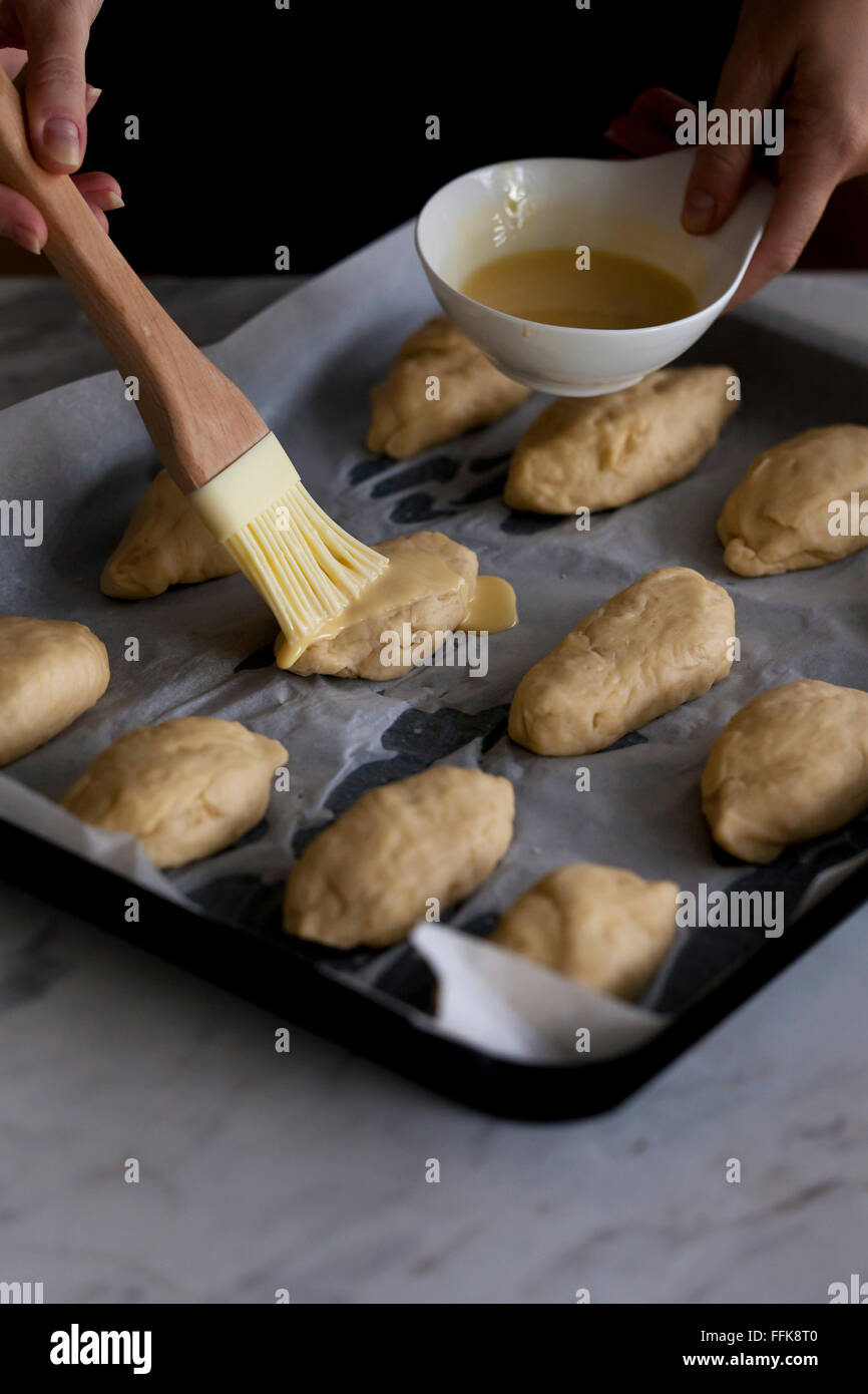 Brushing egg yolk and milk mixture on bread rolls dough Stock Photo Alamy