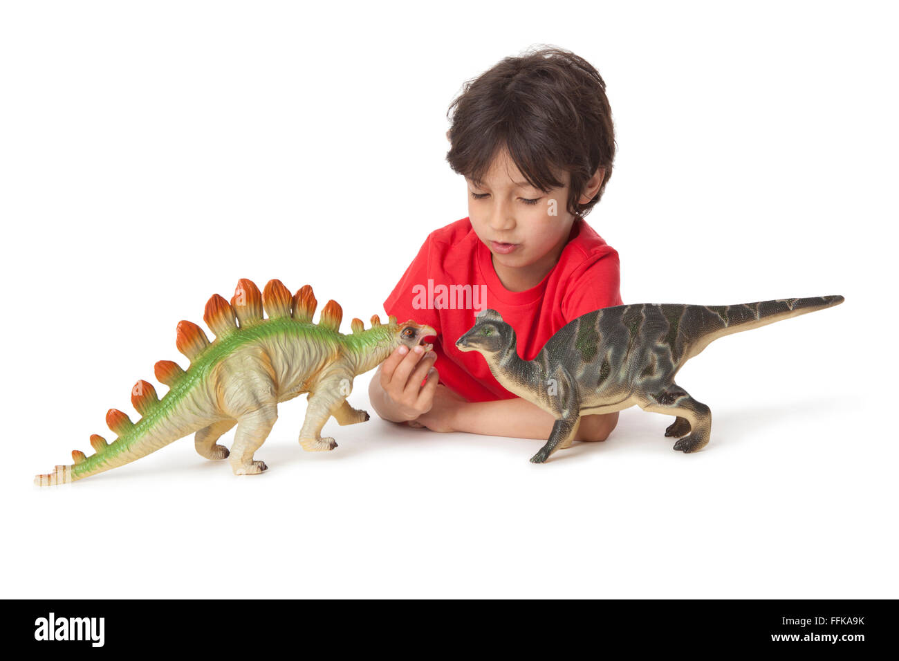 Little boy is playing with two toy dinosaurs on white background Stock Photo