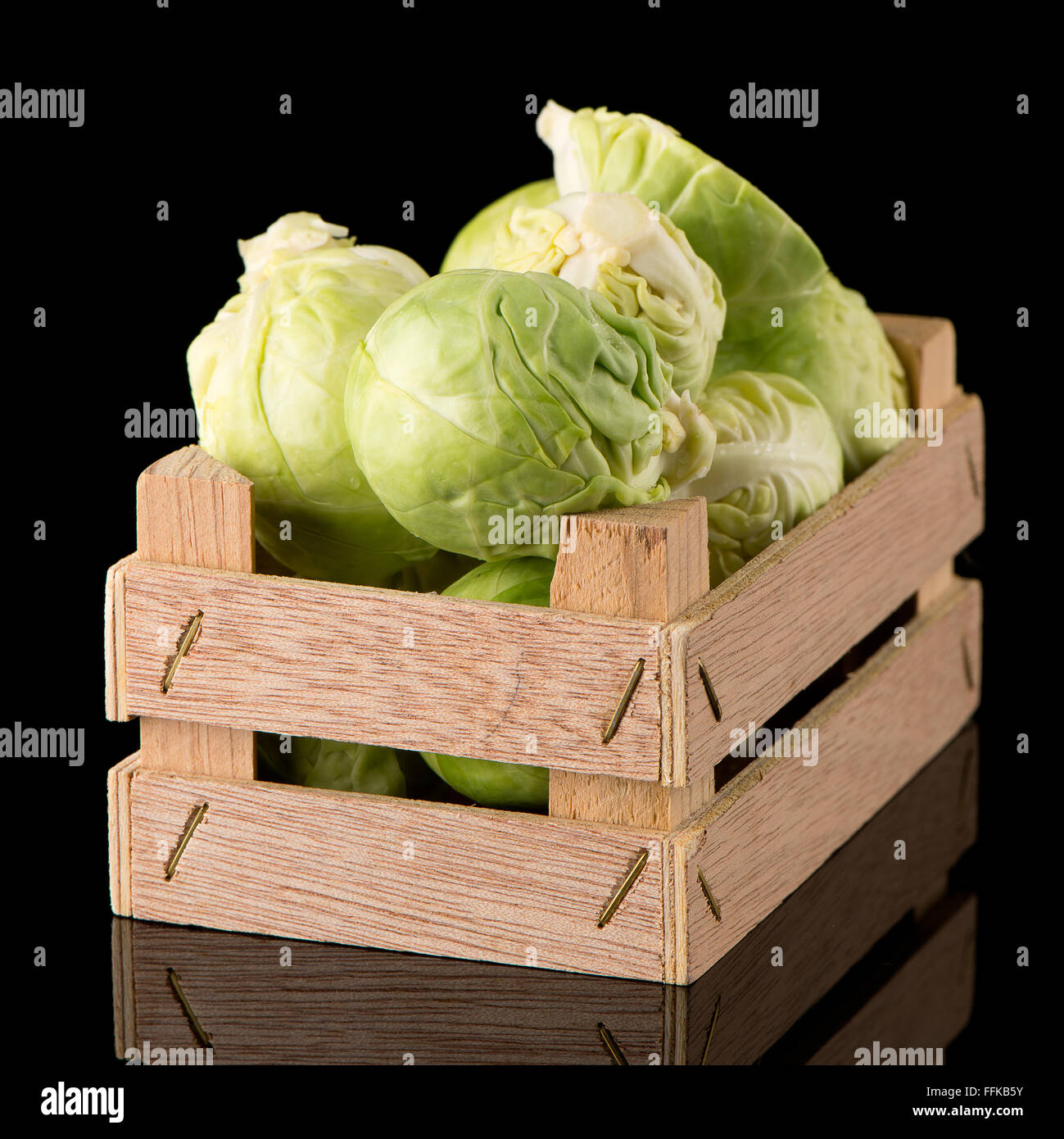 Fresh brussels sprouts on wooden box isolated on black background. Stock Photo