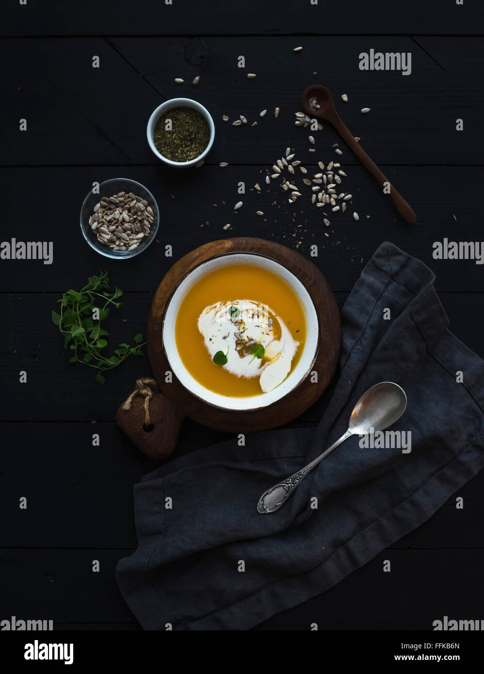 Pumpkin soup with cream, seeds and spices in rustic metal bowl over grunge black background. Top view Stock Photo