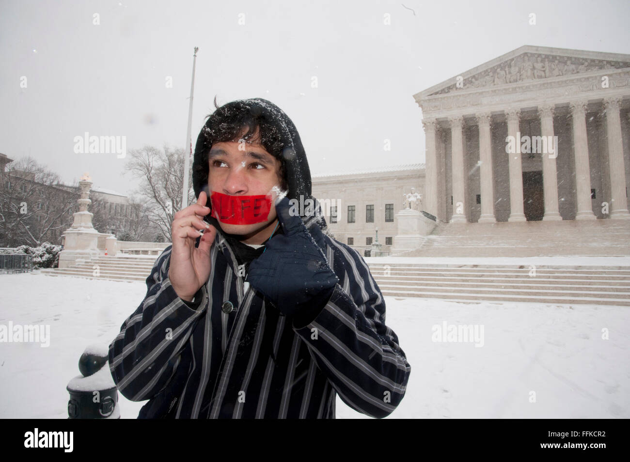 Washington, DC, USA. 15th February, 2016. An unidentified member of an anti-abortion coalition places a tape over his mouth as part of a silent vigil in the snow at the US Supreme Court. Credit:  Patsy Lynch/Alamy Live News Stock Photo