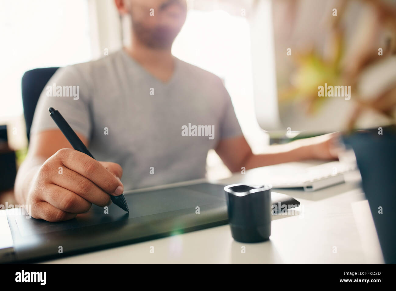 Hand of male designer working at his desk using stylus and digital graphics tablet. Stock Photo