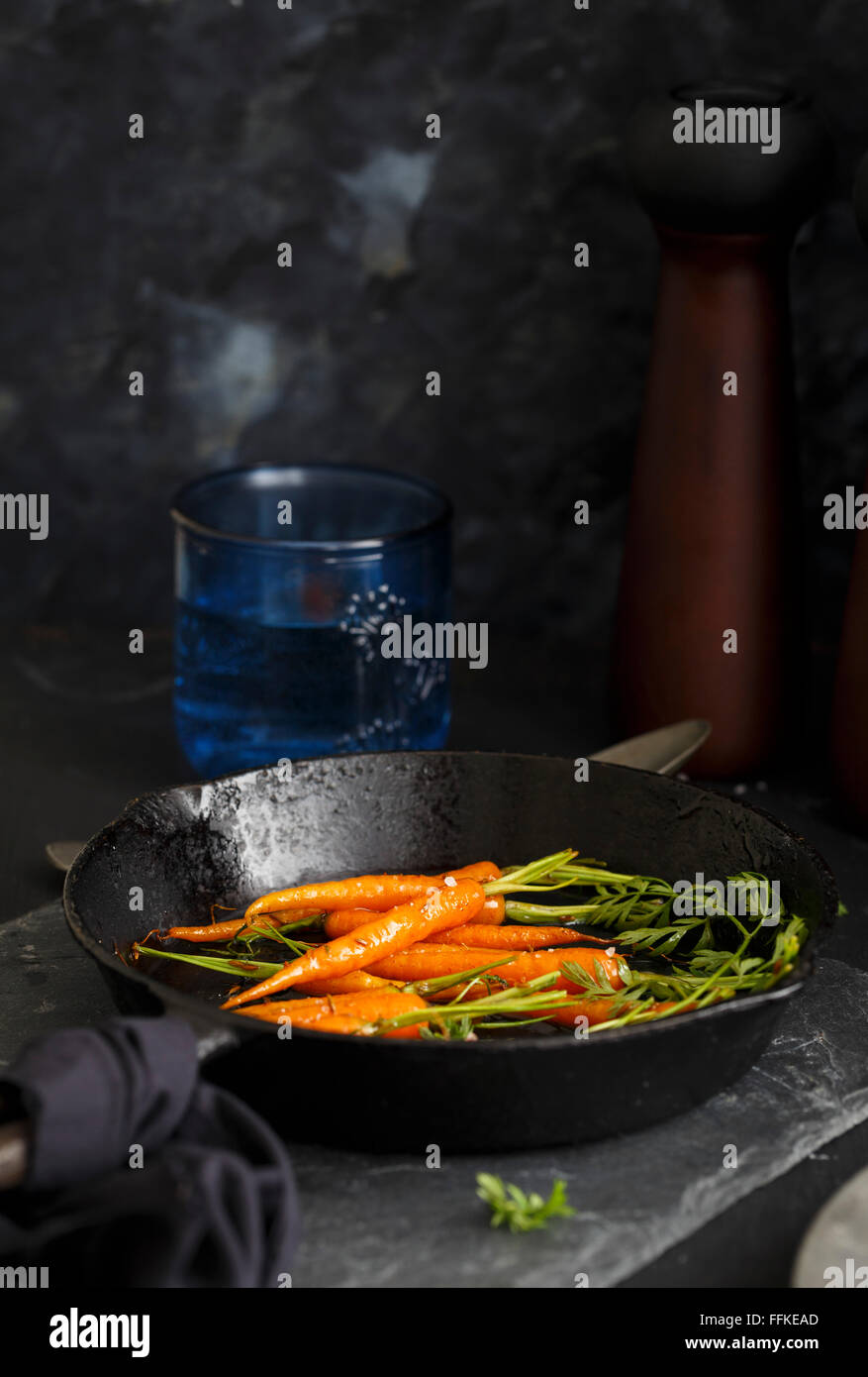 Honey Glazed Carrots on a cast iron pan, in a rustic set up Stock Photo