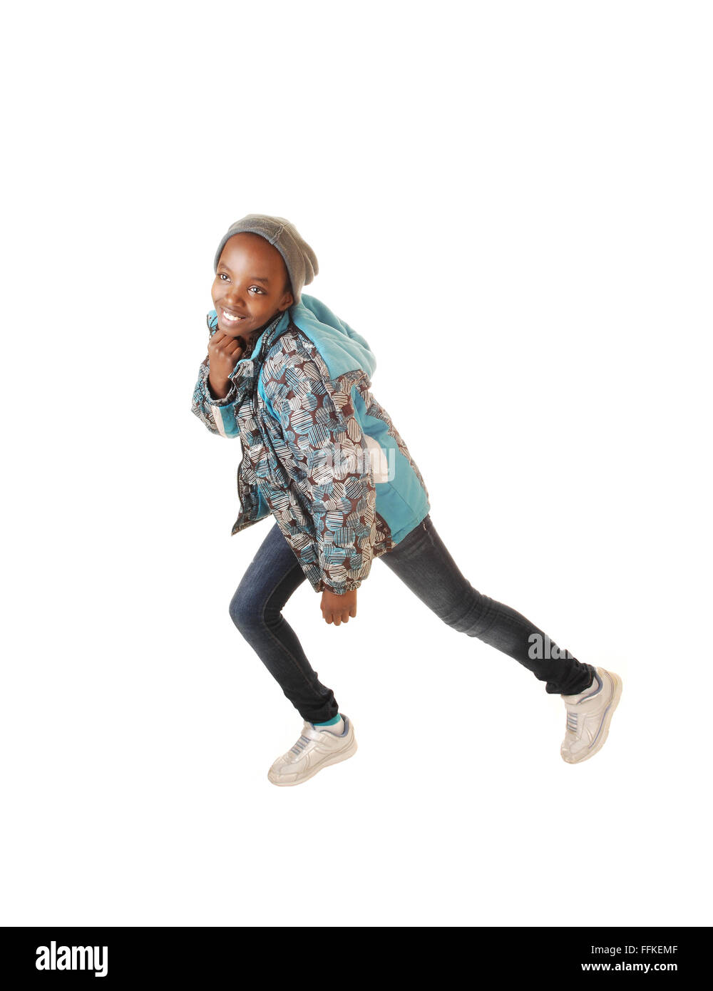 A young pretty black girl in jeans and a blue jacket dancing for white background in the studio. Stock Photo