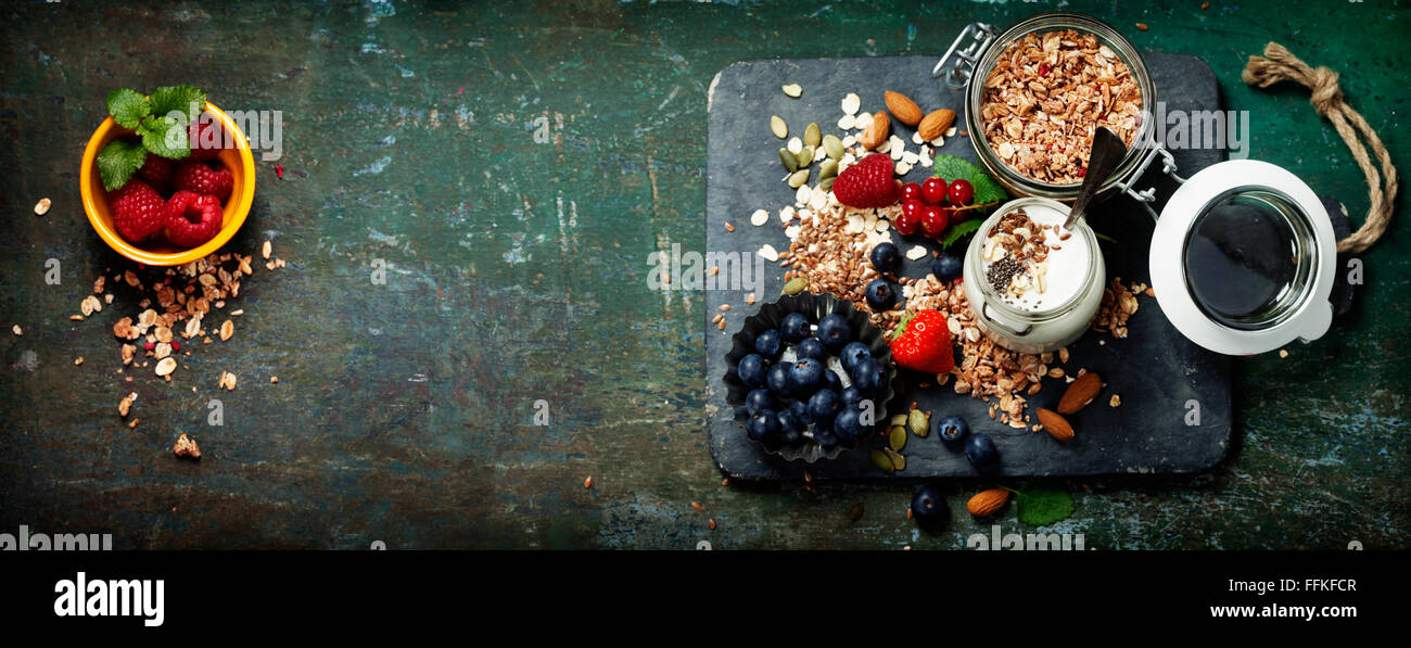 Healthy breakfast of muesli, berries with yogurt and seeds on dark background. Stock Photo